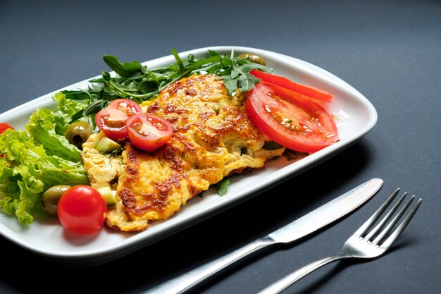 Omelete de tomate servido com salada fresca. Fundo preto