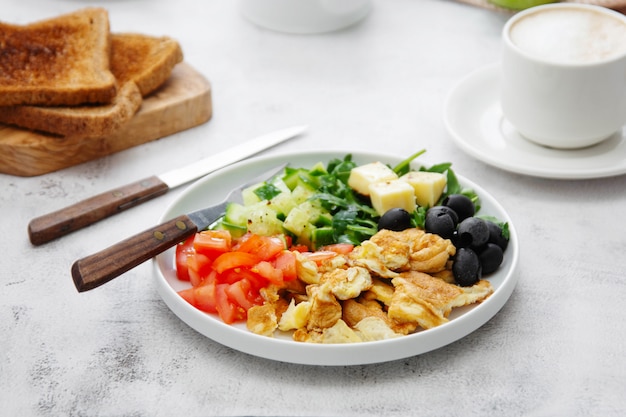 Omelete fresca no café da manhã com legumes, torradas brerad e xícara de café.