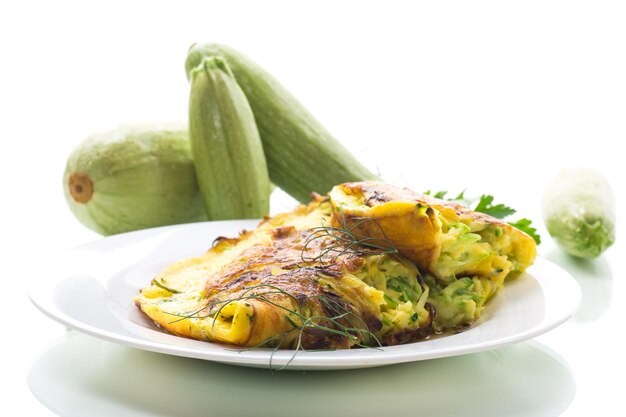 Omelete frita com abobrinha num prato isolado sobre um fundo branco