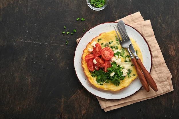 Omelete rústica ou frittatas com cebola verde queijo mussarela verde rúcula e tomate no antigo fundo escuro de madeira Conceito de comida saudável Café da manhã Espaço para cópia Vista superior Mock up