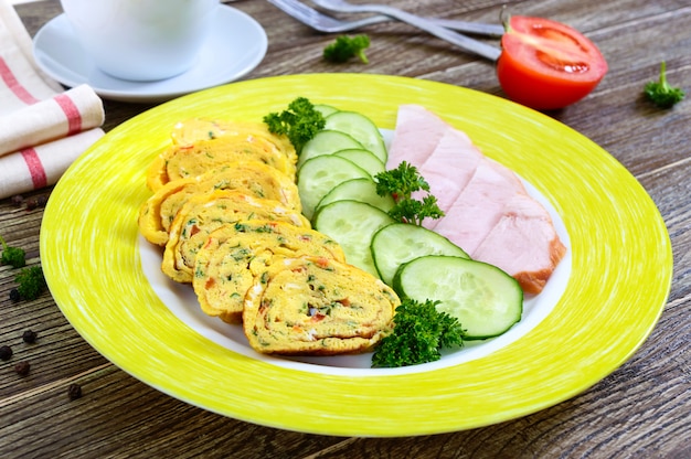 Omelett, Frühlingsrolle mit Schinken und frischer Gurke auf einem Holztisch.