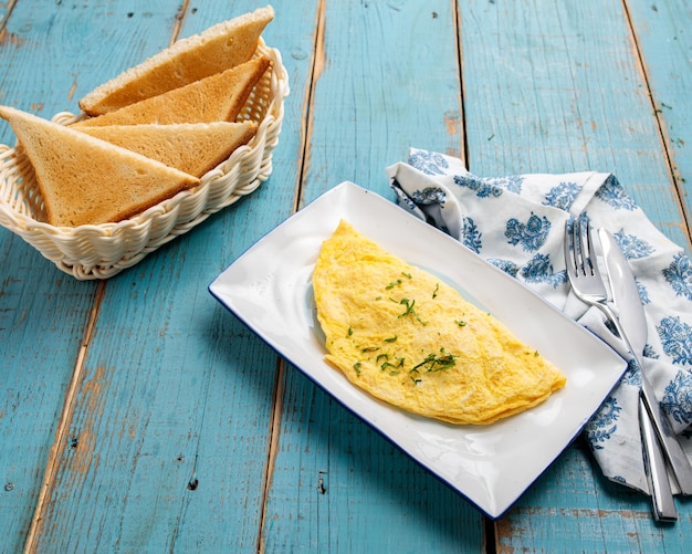 Omelett mit Brot, serviert in einer Schüssel Seitenansicht des Frühstücks isoliert auf Holztisch