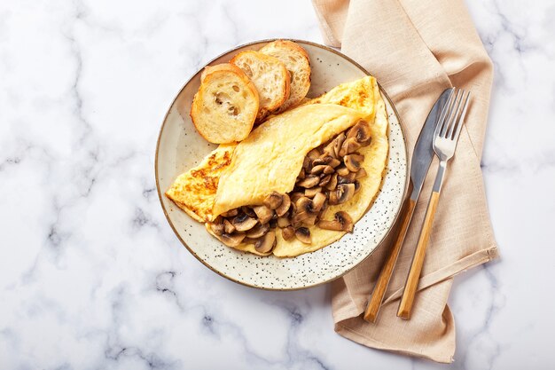 Omelett mit Champignons im Teller auf Marmorhintergrund. Frittata - italienisches Omelett zum Frühstück oder Mittagessen. Flach liegen. Draufsicht, Overhead, Kopierraum