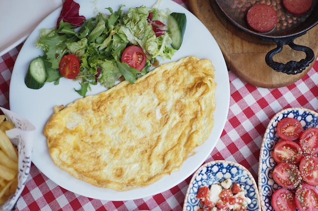 Foto omelett mit gemüsesalat auf weißem teller auf dem tisch