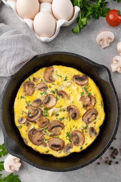 Omelett mit Pilzen und Kräutern in einer Pfanne auf weißem Hintergrund aus Holz Gesundes Frühstück