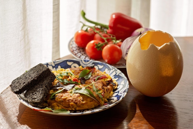 Omelett-Rührei-Straußenei-Shakshuka mit Gemüse und Salat und selbstgebackenem Brot Bio-Lebensmittel vom Bauernhof Kochen von Lebensmitteln Weicher selektiver Fokus