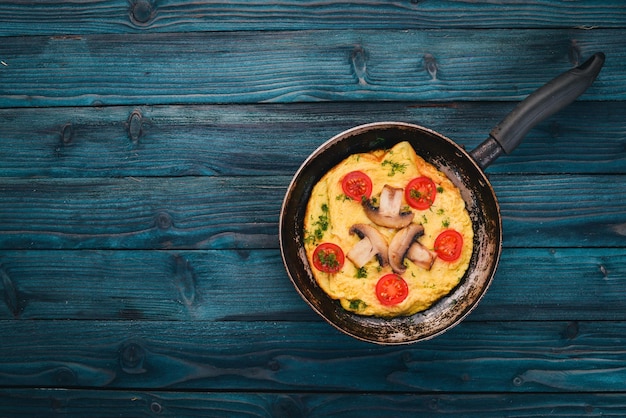 Omelette mit Pilzen und frischem Gemüse und Nüssen in einer Pfanne Auf einem hölzernen Hintergrund Ansicht von oben Kopieren Sie Platz