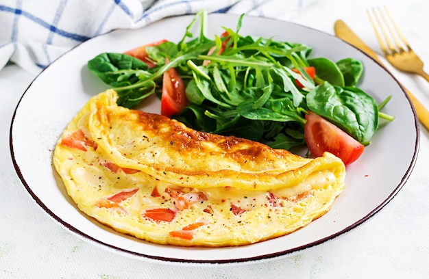 Foto omelette mit tomaten und salat auf weißem teller italienisches omelett frittata