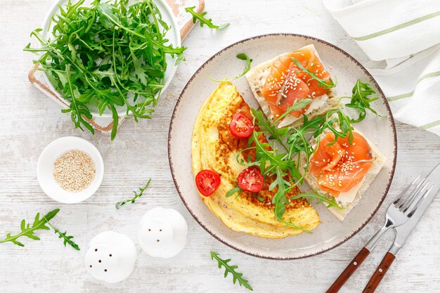 Omelette oder Omelett frischer Rucola und Tomatensalat und Toast mit Butter und gesalzenem Lachs Frühstück Draufsicht