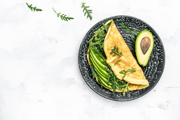 Omelette und Salat mit grünem Gemüse, Avocado und Rucola auf hellem Hintergrund Köstliches veganes vegetarisches Frühstücksbanner-Menü Rezeptplatz für Text Draufsicht