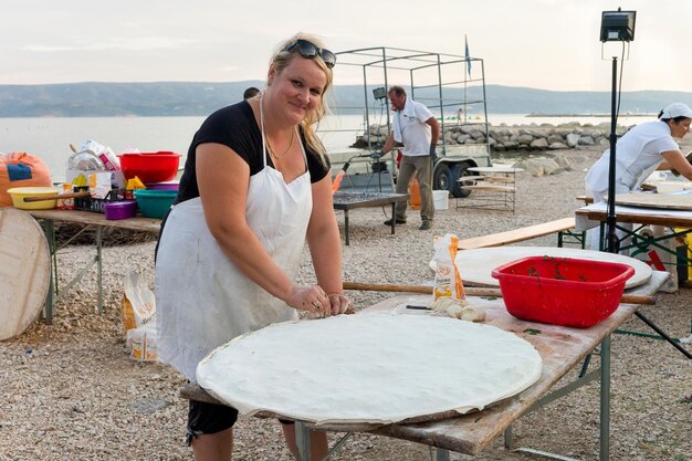 Omis, Croacia - 17 de agosto de 2016: Mujer haciendo masa al aire libre en Omis seasie, Croacia