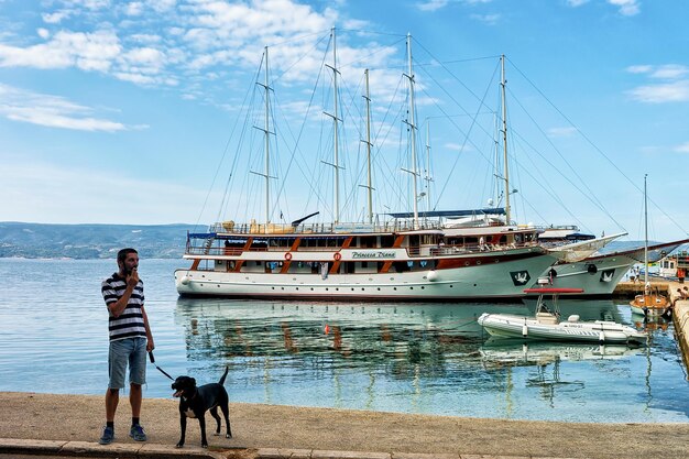 Omis, Kroatien - 18. August 2016: Mann mit Hund am Hafen in der Adria in Omis, Kroatien