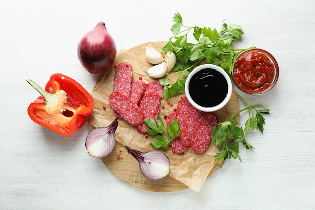 Ã Â¡oncept de comida sabrosa con salchicha de salami sobre fondo de madera blanca