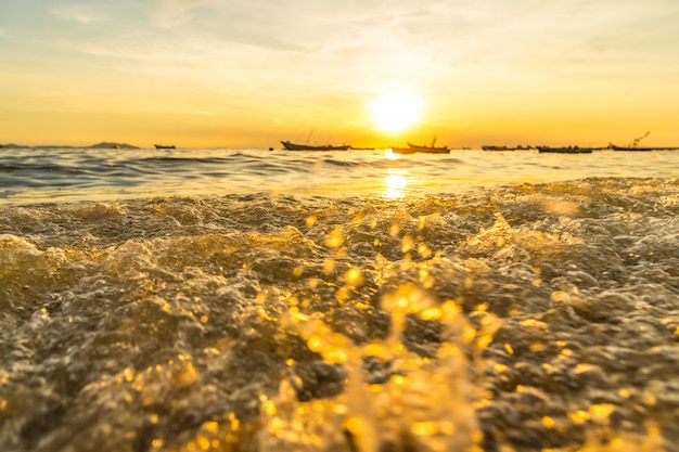 Foto onda atingindo a praia e refletir a luz do sol durante o pôr do sol