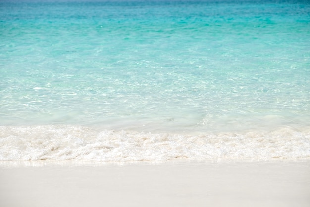 Onda azul do mar na praia da areia. As férias de verão relaxam o fundo com espaço da cópia.