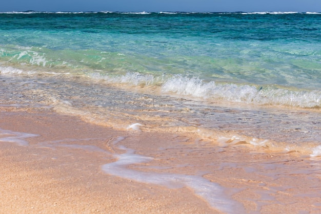 Onda cristalina suave do oceano azul na praia de areia Foco seletivo