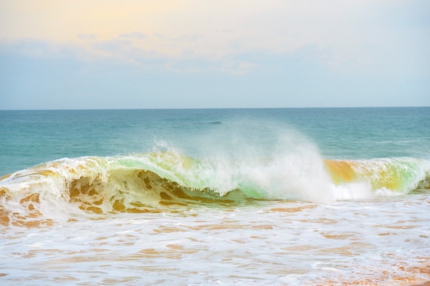 Foto onda de espuma, correndo na costa arenosa.