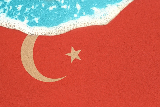 Onda do mar na praia ensolarada com bandeira Turquia vista de cima no surf