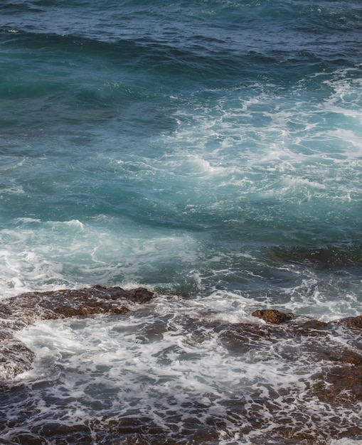 Onda do oceano ao fundo do mar batendo na costa rochosa com spray e espuma antes da tempestade