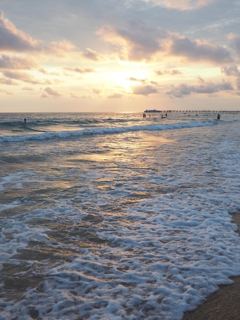 Onda e pôr do sol sobre o mar Belo pôr do sol Ondas espumosas rolam sobre a costa arenosa Vityazevo Anapa Mar Negro Balneário turístico de meca Céu noturno Os raios refletem na água