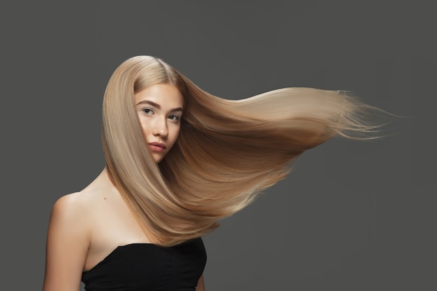 Onda linda modelo com cabelo loiro longo e liso voando no fundo