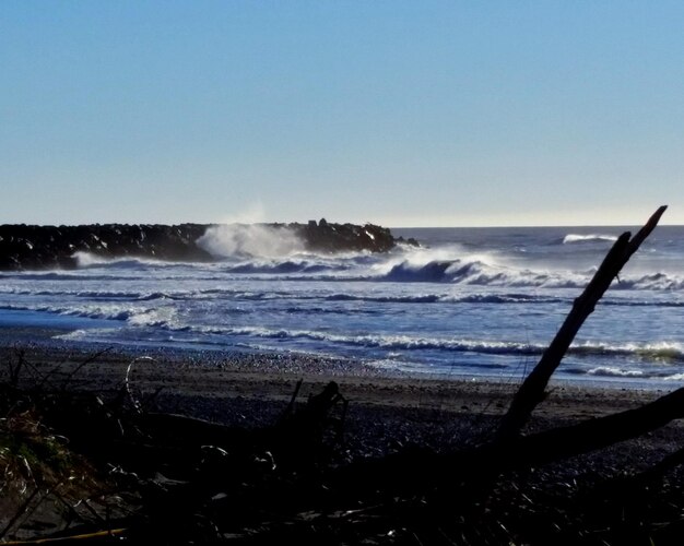 Foto ondas a salpicar na praia contra um céu limpo