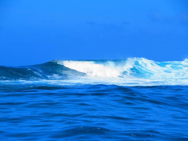 Foto ondas a salpicar no mar contra o céu azul claro