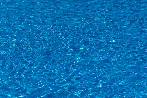 Ondas de agua sobre fondo de piscina de azulejos azules