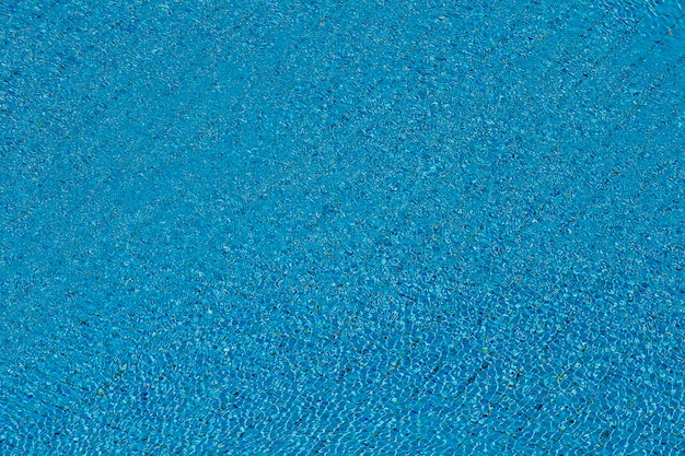 Ondas de agua sobre fondo de piscina de azulejos azules