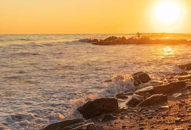 Ondas azuis escuras contra o belo pôr do sol laranja no mar negro, anapa, rússia