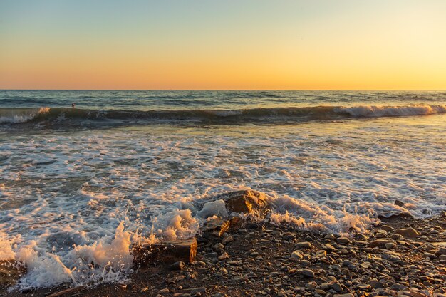 Ondas azuis escuras contra o belo pôr do sol laranja no mar negro, anapa, rússia