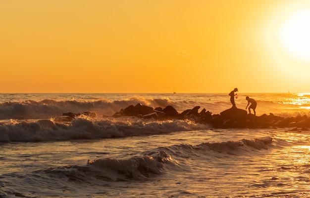 Ondas azuis escuras contra o belo pôr do sol laranja no Mar Negro, Anapa, Rússia