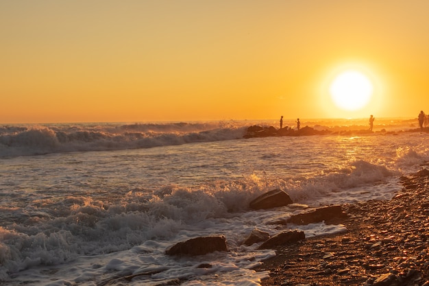 Ondas azuis escuras contra o belo pôr do sol laranja no Mar Negro, Anapa, Rússia