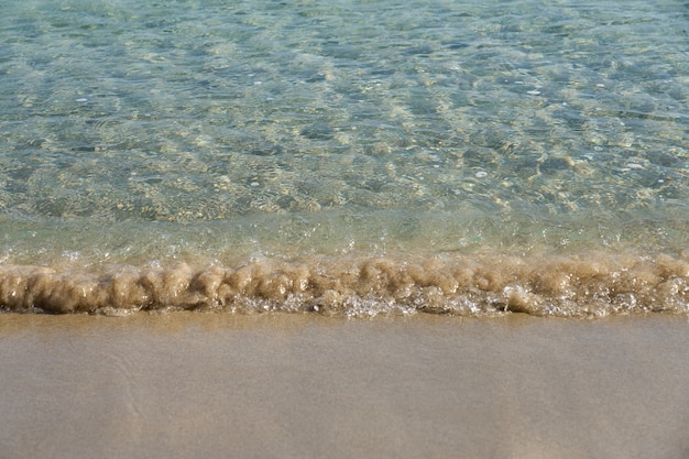 Ondas claras e areia colorida na praia tropical em Creta, Grécia.