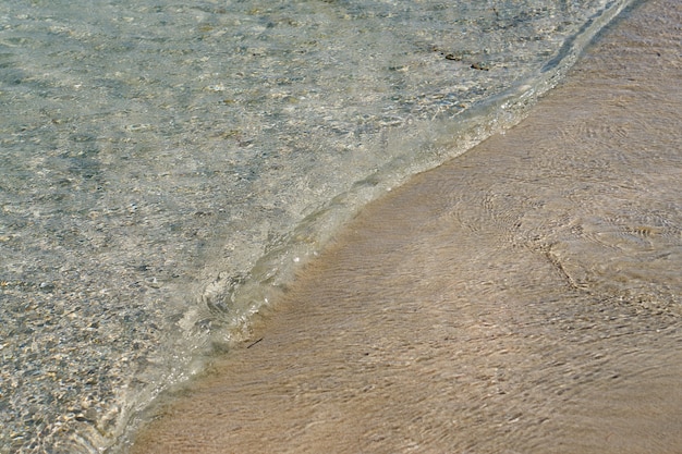 Ondas claras e areia colorida na praia tropical em Creta, Grécia.