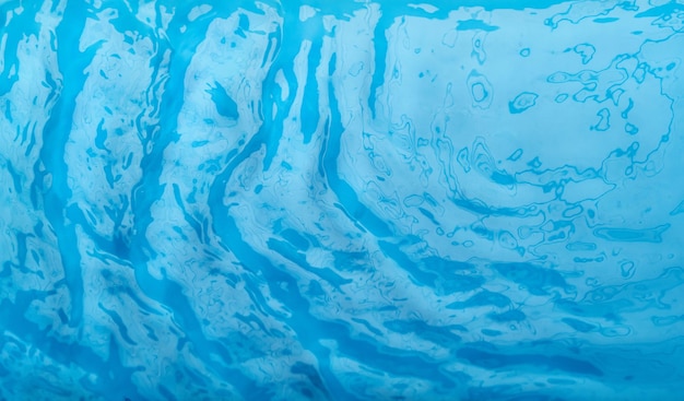 Ondas de água azuis transparentes e desfocadas na superfície do fundo azul da água