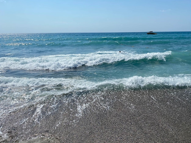 Ondas de água no mar e areia com pequenas pedras naturais multicoloridas à beira-mar pequenas