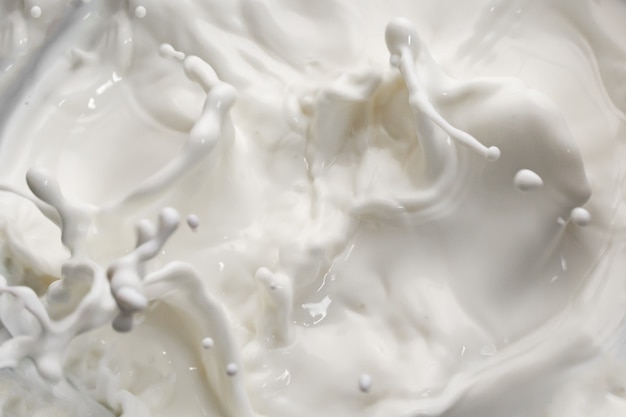 Ondas de leite espirrando fundo branco isolado