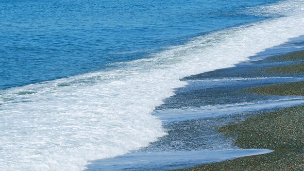 Ondas de praia calmas na costa ondas do mar e surfes estão espalhando seixos e seixos pequenos na costa