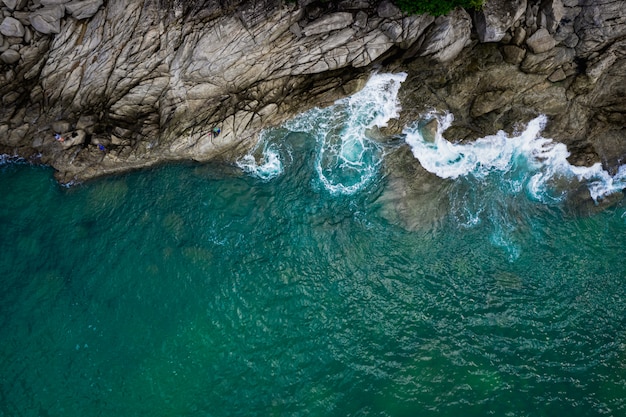 Ondas do mar atingindo rochas e pescadores de pequeno porte na ilha de Phuket, Tailândia