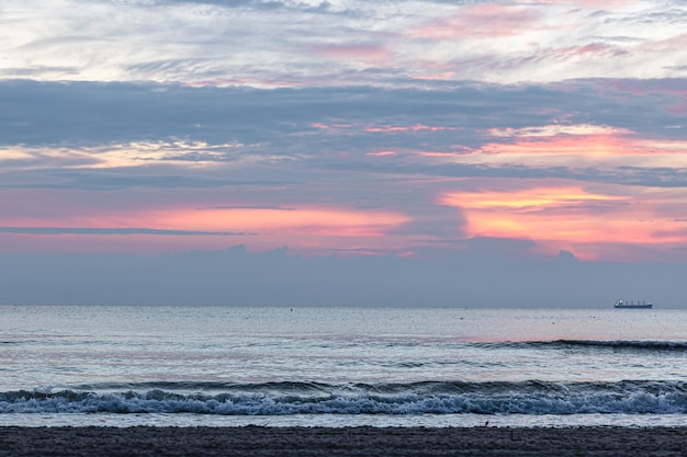 Ondas do mar de textura ao pôr do sol com nuvens cor de rosa