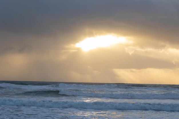 Ondas do mar e luz rompendo as nuvens no céu