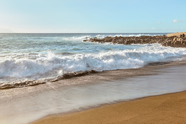 Ondas do mar na costa ao pôr do sol de verão