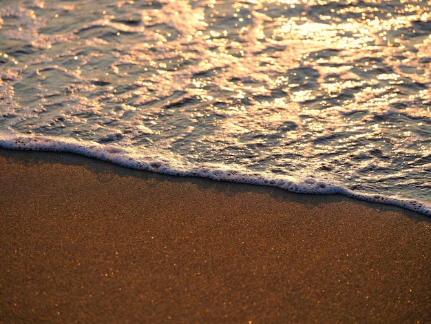 Ondas do mar na praia ao pôr do sol