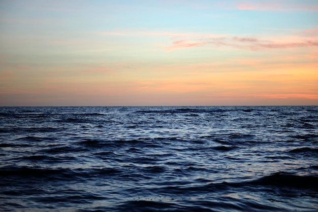 Ondas dramáticas do oceano vermelho ao pôr do sol com água escura do mar suave à noite