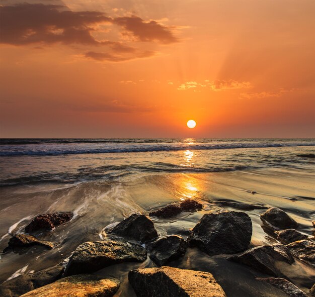 Ondas e pedras na praia do pôr do sol