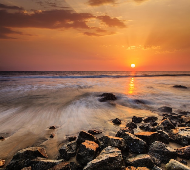 Ondas e pedras na praia do pôr do sol