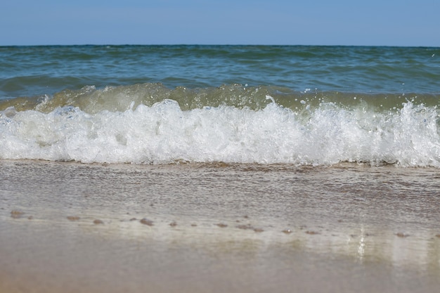 Ondas espumosas do mar rolam na praia durante o dia