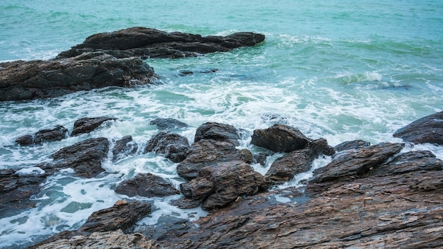 Ondas quebrando para as rochas na costa criando espuma do mar e bolhas