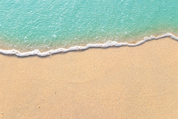 Ondas suaves com espuma de oceano azul na praia de areia